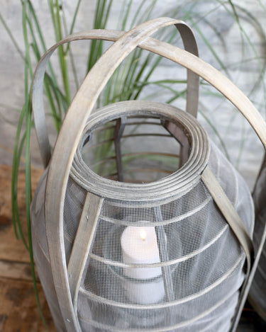 Wicker and mesh lantern with glass insert for candle in lifestyle photo