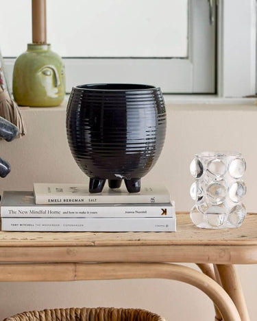 Black glazed flower pot on feet in lifestyle photo