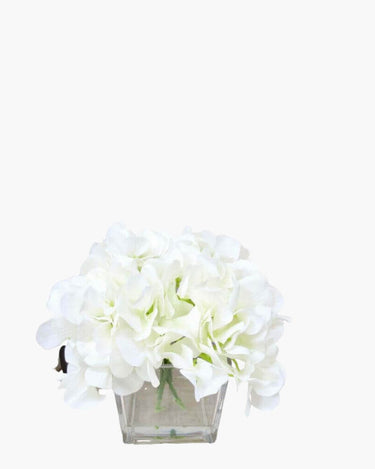 Faux silk Hydrangea arrangement in cubed glass vase on white background